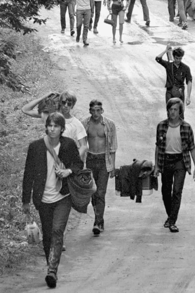 A Group of People Walk Down the Road at the Woodstock Festival